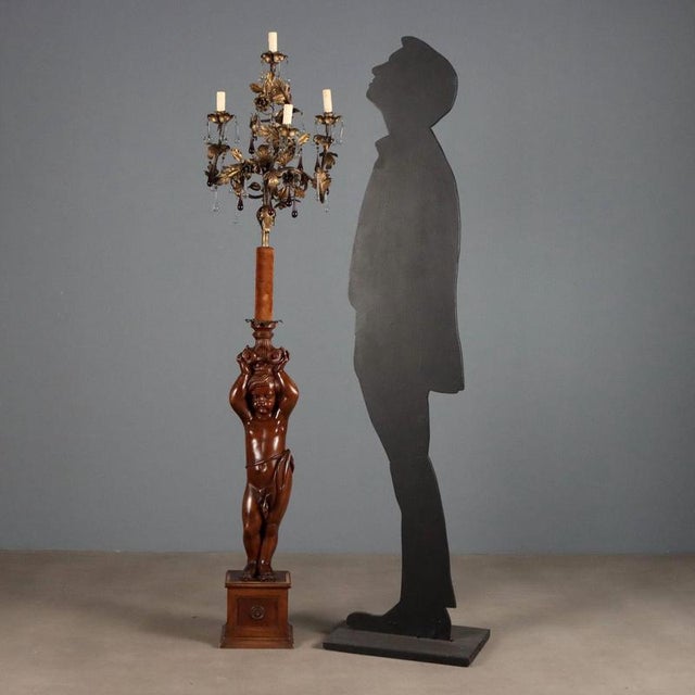 Late 19th-century floor lamp from Italy, featuring an artistic carved wooden base depicting a putto holding a candelabrum....