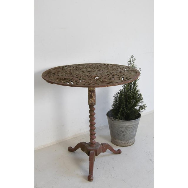 Small round bistro table or garden table made of cast iron with original old red colour finish. from around 1900. Standing...