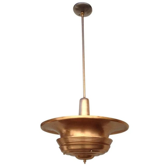 Art Deco era streamlined copper ceiling hanging pendant with a large copper saucer shade connected to a hanging stem....