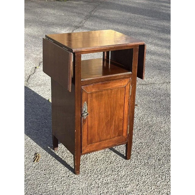 Edwardian bedside cabinet. In mahogany with fold out flaps. Sizes :- 75 cms tall, 47 cms wide, 37 cms depth. Has wear as...