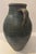 A rustic hand-thrown terracotta amphora with a bulbous body and two loop handles rising from the shoulder to the neck. The...