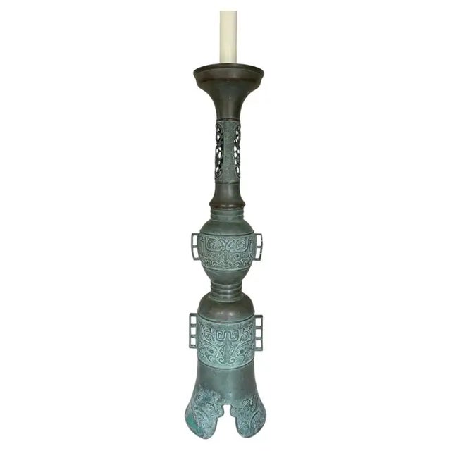 Monumental bronze table lamp in the style of James Mont. This tall sculptural Chinoiserie lamp features a handled...