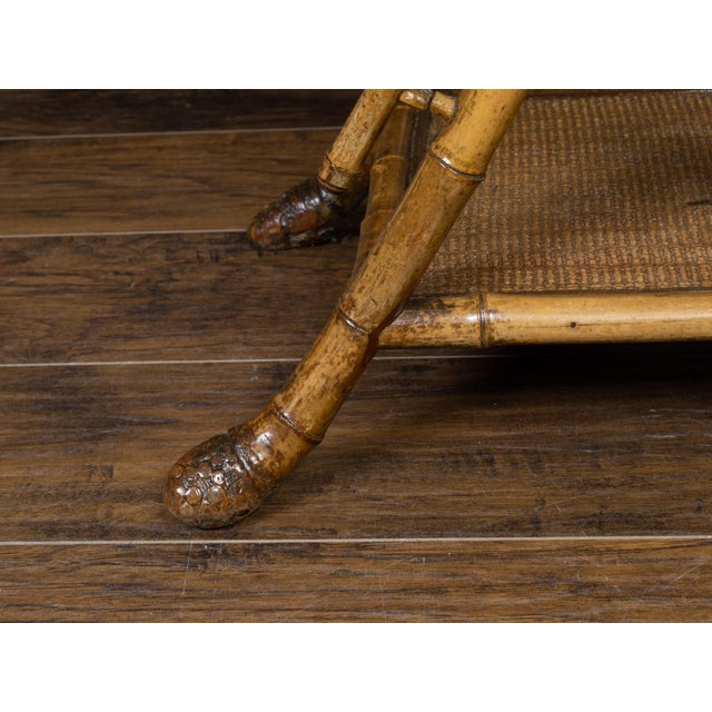 An English Chinoiserie style bamboo side table from the early 20th century, with rattan accents. Created in England at the...