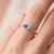 A cool, minimalist solitaire featuring a brilliant blue marquise-cut topaz set in an east-west orientation, held by a...