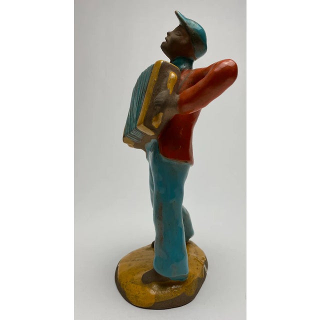 Rare and beautiful Art deco figure of an accordion player, glazed in vibrant blue, orange and yellow color, designed Etha...