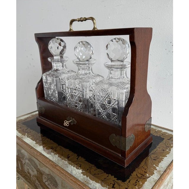 This is a beautifully crafted tantalus, a traditional liquor decanter set designed to secure and display fine spirits. The...