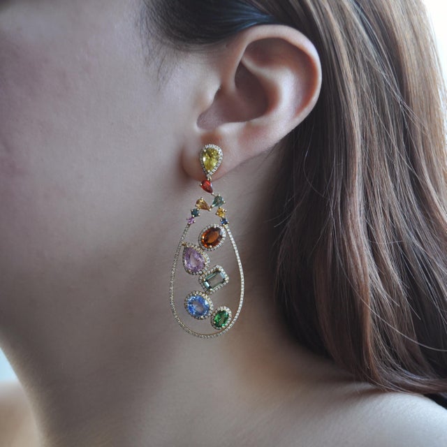 A striking pair of rainbow multi-color sapphire and diamond drop earrings crafted in 18 karat yellow gold, designed in an...