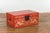A Chinese red lacquered blanket chest from the 20th century, with gilt décor depicting guardian lions, flowers, scrolling...