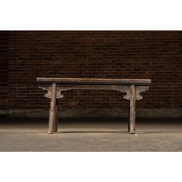 Antique low wooden bench with shaped apron. Handcrafted East Asian vernacular bench featuring a single-plank top over...
