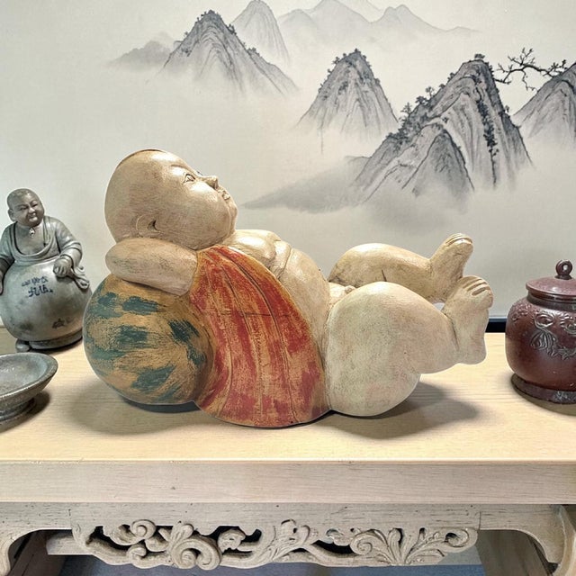 Vintage Chinese hand-carved wooden figure depicting a reclining lucky baby or Karako-style child resting upon a melon...