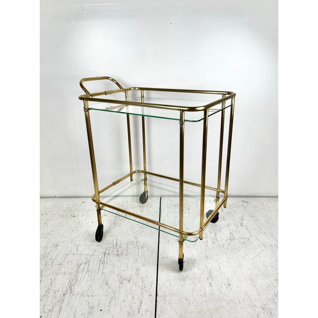Vintage art deco style brass bar cart. Solid brass piping frame with rounded corners. Two glass shelves. On wheels.