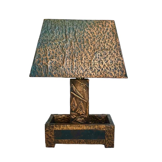 Wonderfully textural and featuring a rich patina, this hammered-copper clad table lamp includes a base having a scenic...