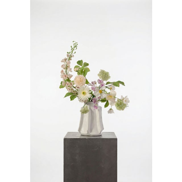 A light, airy arrangement featuring white tulips, cream dahlia, and delicate lilac sweet pea. Soft greenery and Queen...