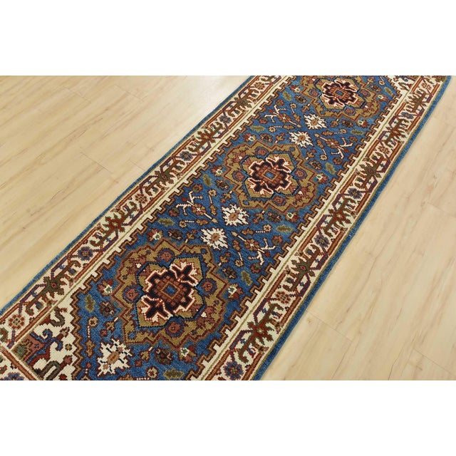 A traditional tribal Heriz runner hand-knotted with an all-wool pile on a cotton foundation. This oriental rug features...
