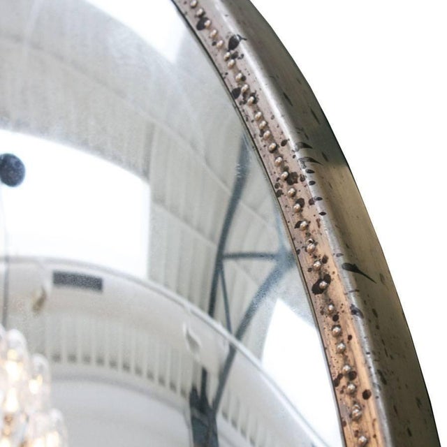 Large circular wall-mounted convex mirror with patinated textured metal frame. Due to its shape it will reflected all the...