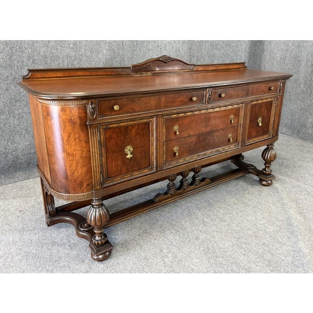 This circa 1930s Jacobean-style sideboard showcases richly figured wood, substantial turned supports, and finely detailed...