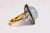 A large oval cabochon aquamarine gemstone bordered in black onyx and round, brilliant cut diamonds in a pave` setting. A...