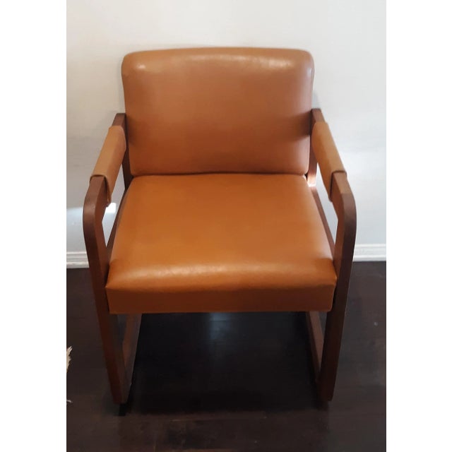 Great 1960/70s library armchair made of solid dark reddish wood with rounded edges. Upholstery is soft vinyl in a light...