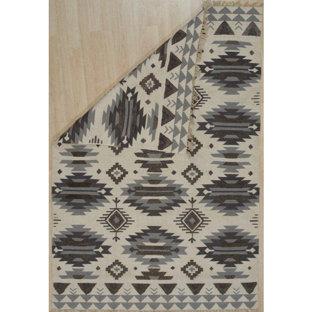 This flat weave rug is crafted from durable polyester fibers and features a neutral color palette of ivory, beige, cream,...