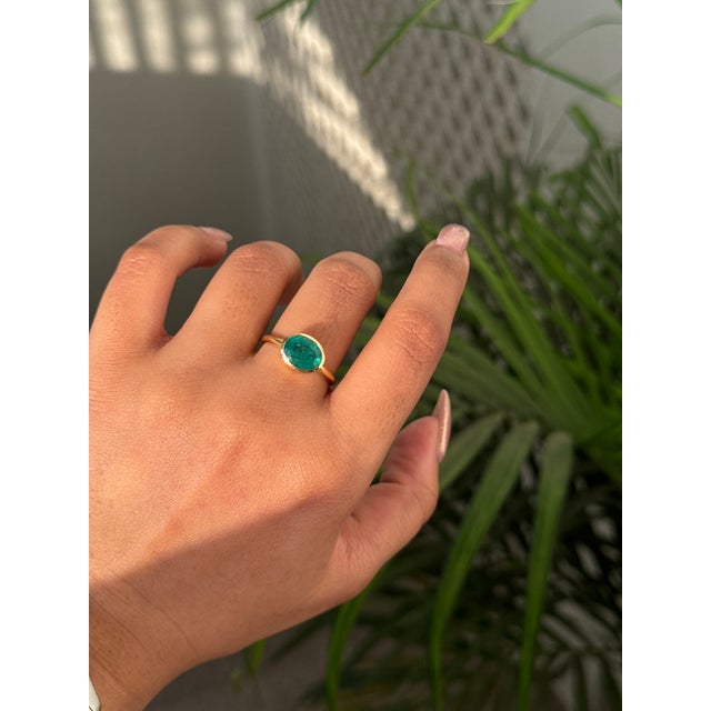 This solitaire bezel set ring featuring a 1.64 carats natural oval-cut emerald set in 18K yellow gold. The emerald...