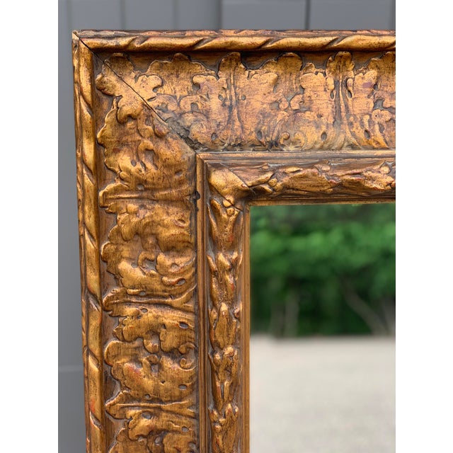 A striking antique-style carved giltwood wall mirror with rich Baroque/Rococo influence. The substantial frame features...