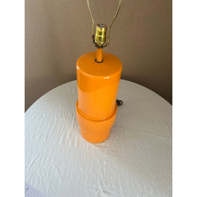 Vintage Mid-century Modern cylindrical table lamp in orange. Includes harp and finial 23" tall from bottom to top of socket.