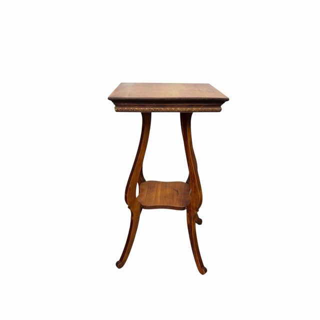 This is a vintage two-tier wooden occasional or drinks table, featuring a square top with carved egg and dart apron...