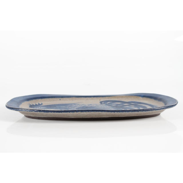 Large oblong ceramic dish with blue and grey matte glaze showing a peacock motif, hand-made and hand-painted by Thomas...