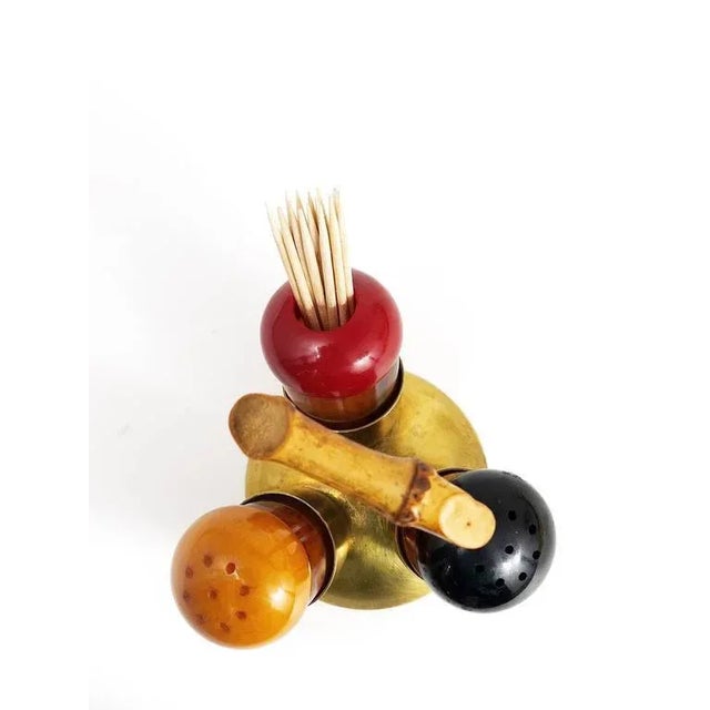 A charming modernist cruet set, consisting of salt and pepper shakers and a toothpicks Stand. Made of brass, bakelite in...