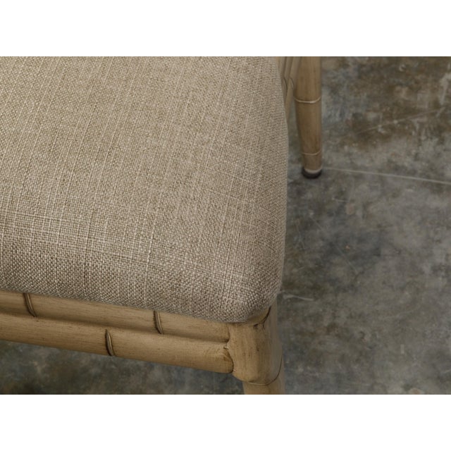 A pair of faux bamboo side chairs from the mid 20th century with saber legs and new linen upholstery. Created during the...