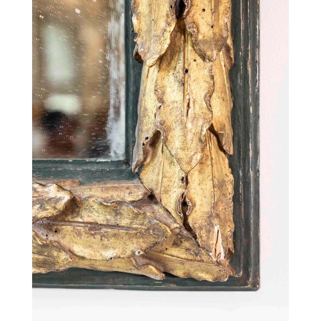 Elegant mirror in carved Swiss pine wood gilded with pure gold leaf, painted in a shade of antique green. The frame is...