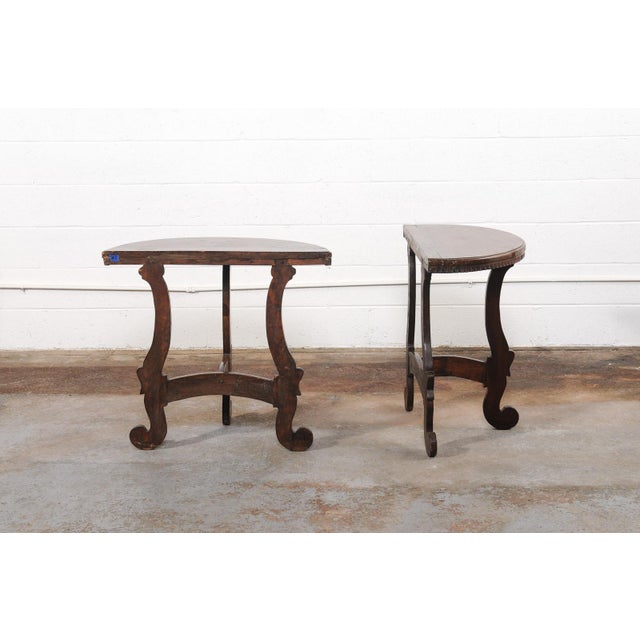 A charming Italian pair of carved wood demi-lune tables from the 19th century. These smaller-sized antique consoles from...