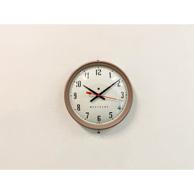 This wall clock was produced by Westclocx in Canada during the 1960s. It features a brown iron frame, a metal dial and a...