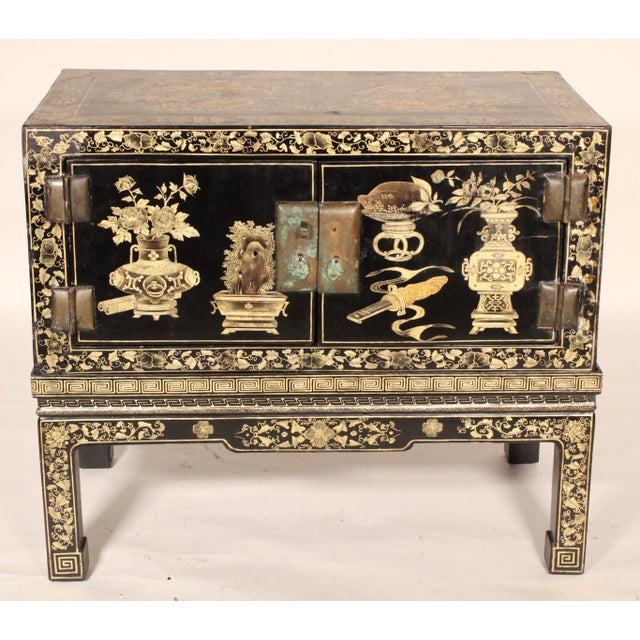 Chinese black lacquer and gilt decorated two door trunk on stand, circa 1930's. With a rectangular top with gilt decorated...