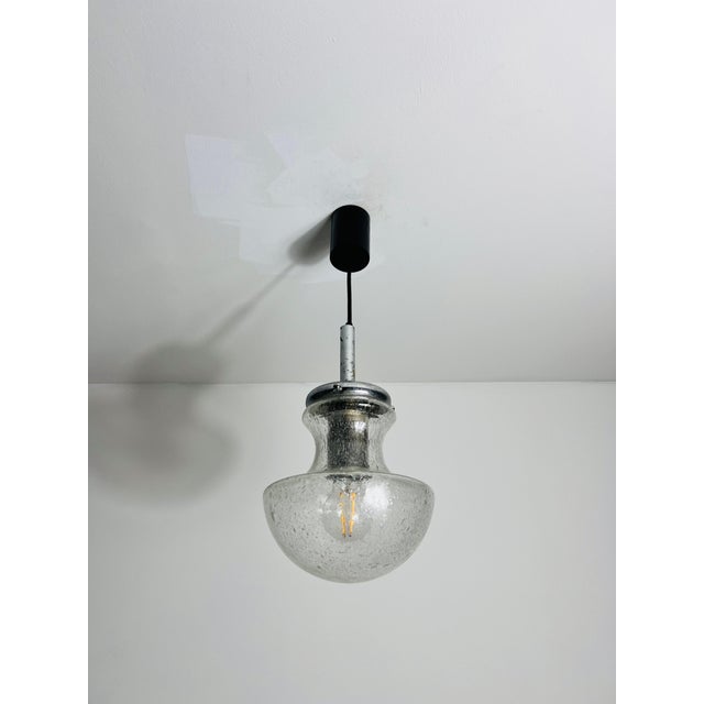 A stunning glass hanging lamp made in Germany in the 1970s. This elegant light fixture features exquisite Murano glass,...