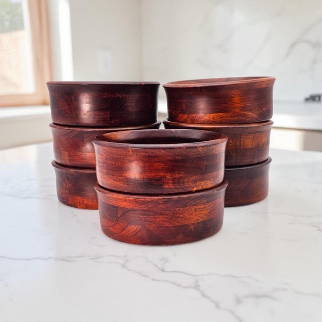A cohesive set of eight hand-turned cherry wood bowls, executed in solid hardwood and showcasing the rich tonal depth...