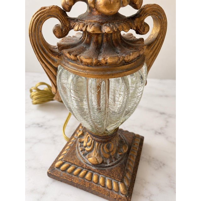 Elegant Antique table lamp featuring an elaborate textile shade in warm beige and burgundy tones, richly decorated with...