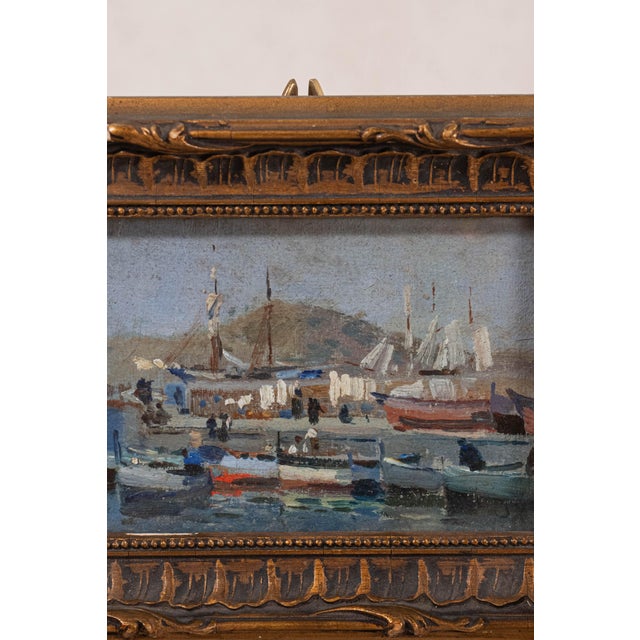 Antique French oil on board depicting boats in a harbor. Presented in a carved wood frame with gilt finish.