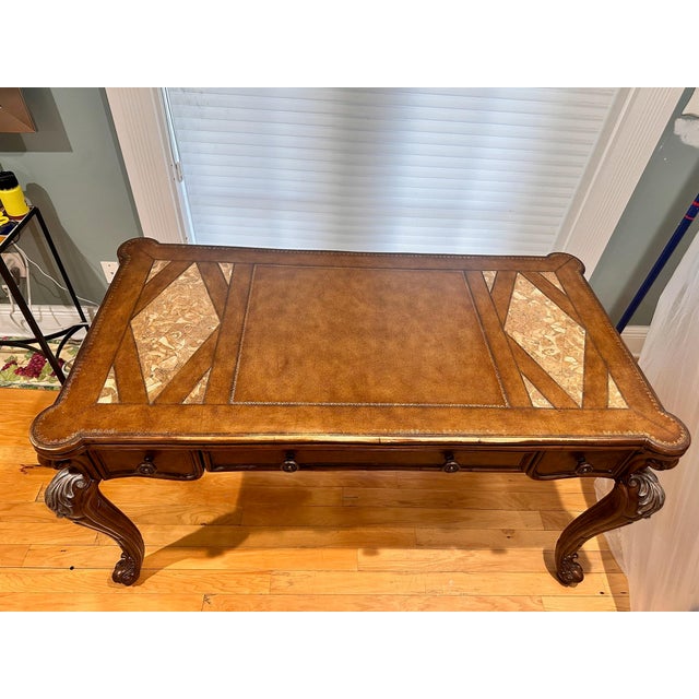 An elegant traditional executive writing desk featuring a genuine leather writing surface accented with real marble inlays...