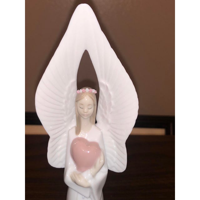 An exquisite, retired porcelain bell figurine by Lladró titled "Campana Angel Corazon" or "Sounds of Love" (Ref. #06474)....