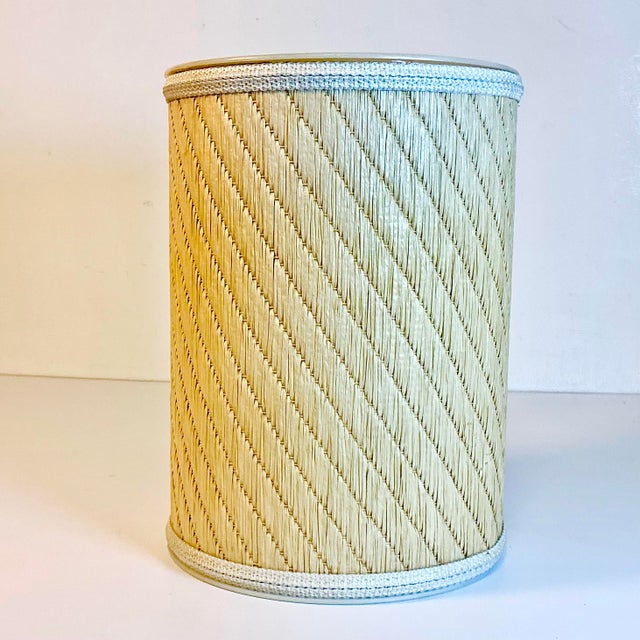 Offering a Mid-Century designed wastebasket from the 1960s. The basket is plastic covered in a woven raffia fabric and...