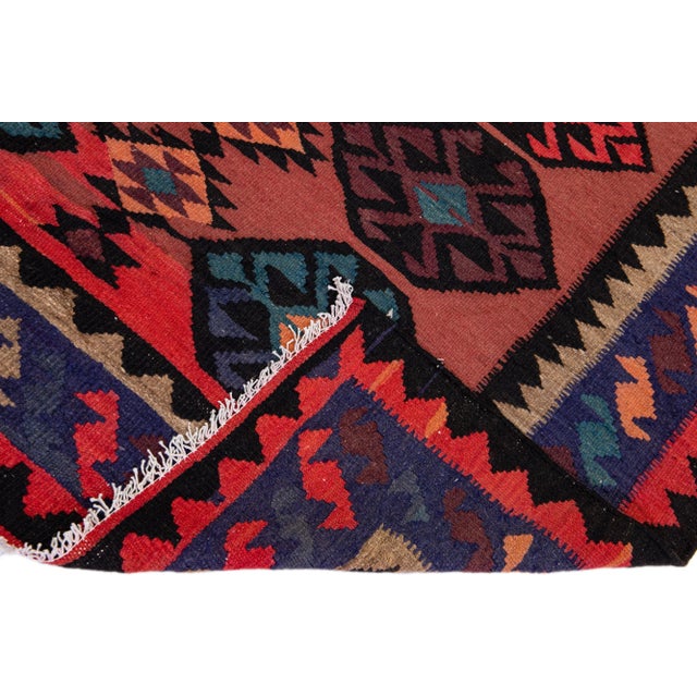 Beautiful vintage Turkish Kilim hand-knotted wool rug with a red field. This piece has a navy blue frame and multicolor...