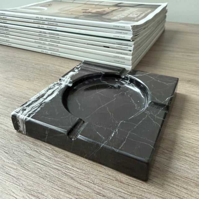 Handcrafted from richly veined black marble, the Naya Ashtray is defined by its clean square silhouette, recessed circular...