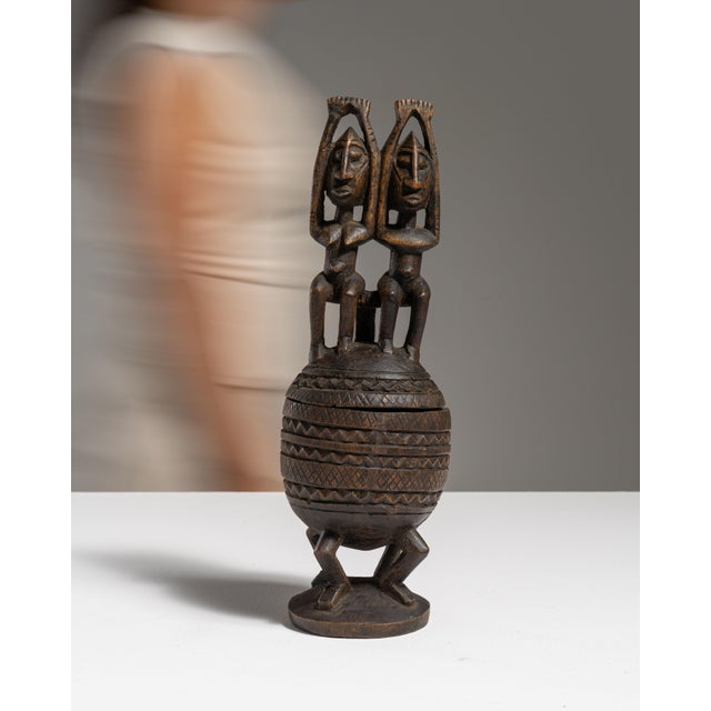 This 20th century African hand-carved lidded vessel with caryatid figures from Africa is carved in dark wood as a lidded...