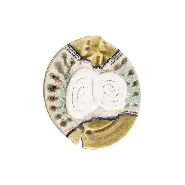 A studio pottery wall plate or charger. The surface of this plate features an abstract design in green and blue, with two...