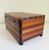 Large primitive, folk art-style lidded box made from contrasting bands of stained pine wood with four arched feet. Lid is...