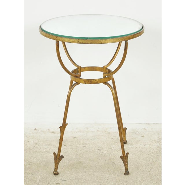 Vintage European round side table with a gilded wrought iron frame and a mirrored top. The mirror displays signs of fading...