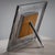 Large tabletop picture frame with a back stand and a wide metal border featuring a slightly convex surface. A decorative...