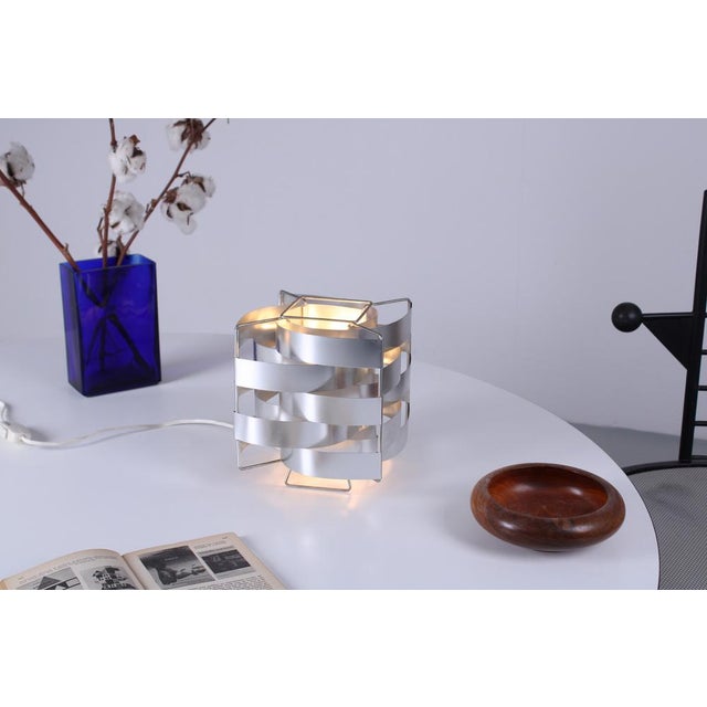 Light weight iconic French table lamp made of a metal frame with thin aluminium slat cover. Provides a refined, warm...