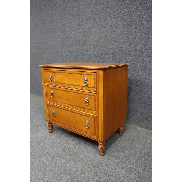 Tiger maple chest by Councill with three drawers. Classic form with banded inlay detail and lion’s head ring pulls. Turned...